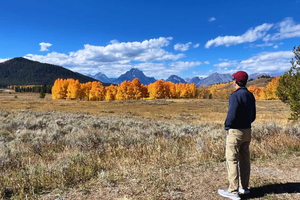 A man savors the view of fall foliage and mountains in Grand Teton National Park, Wyoming.