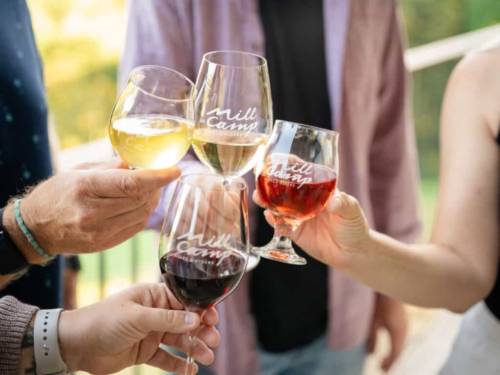 Four people clink wine glasses at Mill Camp to celebrate a Stick Season getaway.