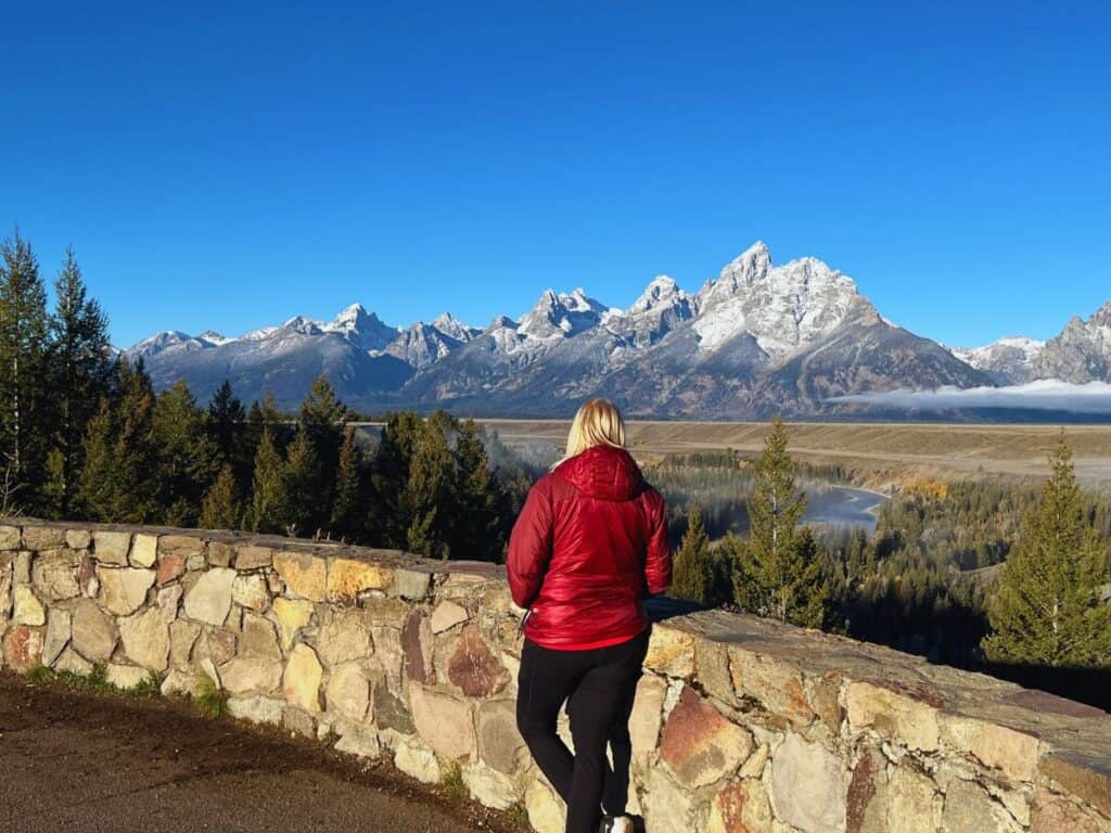A woman enjoys the view of mountains in Grand Teton National Park from Snake River Overlook.