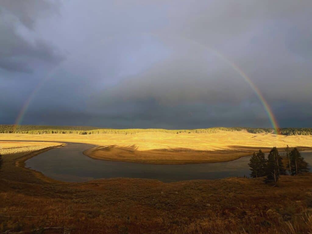 A rainbow stretches across the sky in Hayden Valley, Yellowstone National Park, WY.