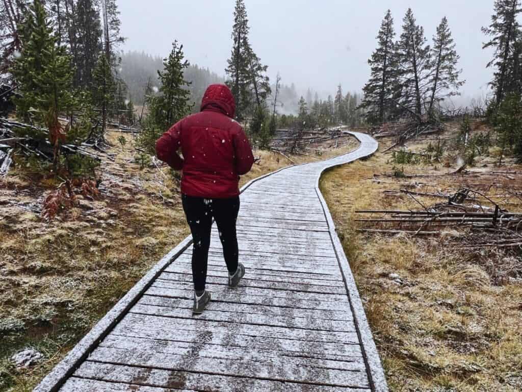 A woman walks a snow-dusted boardwalk trail in Yellowstone National Park, WY.