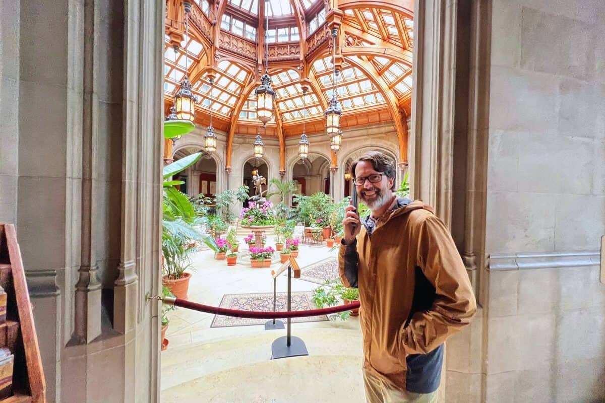 A man holds a device up to his ear on the self-guided audio tour of Biltmore mansion.