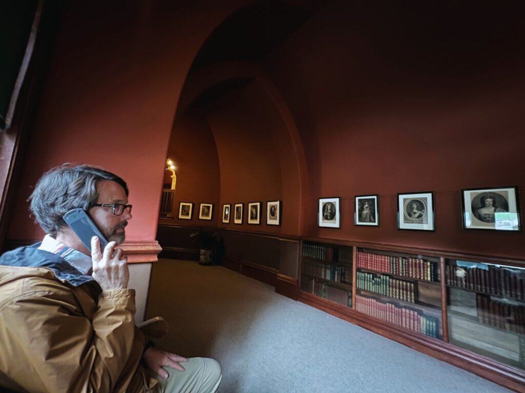 A man sits on a bench with a handheld device up to his ear during the Biltmore audio tour.
