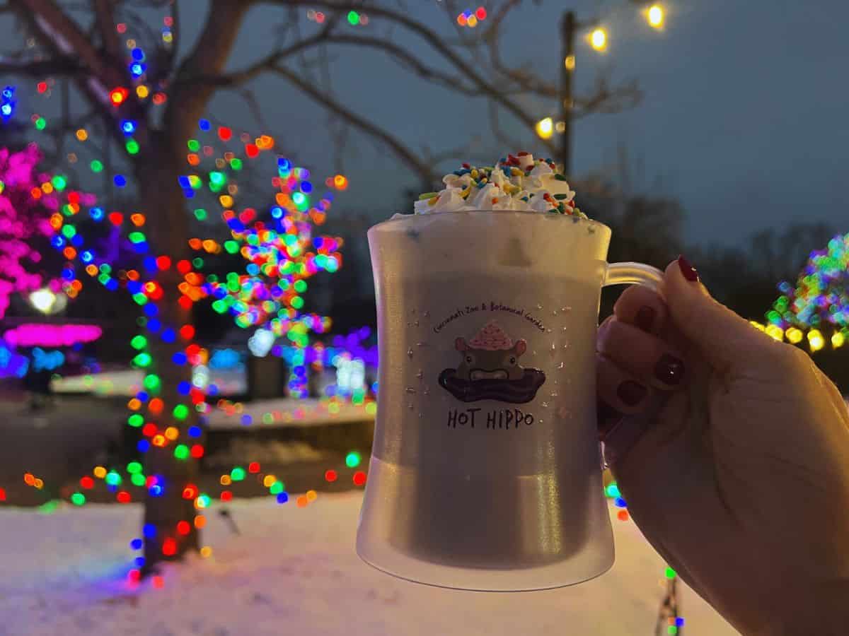 A woman's hand holds up a mug of hot cocoa - the Hot Hippo Purple Hot Chocolate Drink