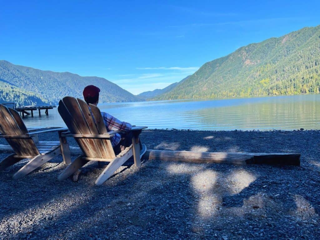 A man relaxes in an Adirondack chair along the shore of Lake Crescent, Olympic National Park.