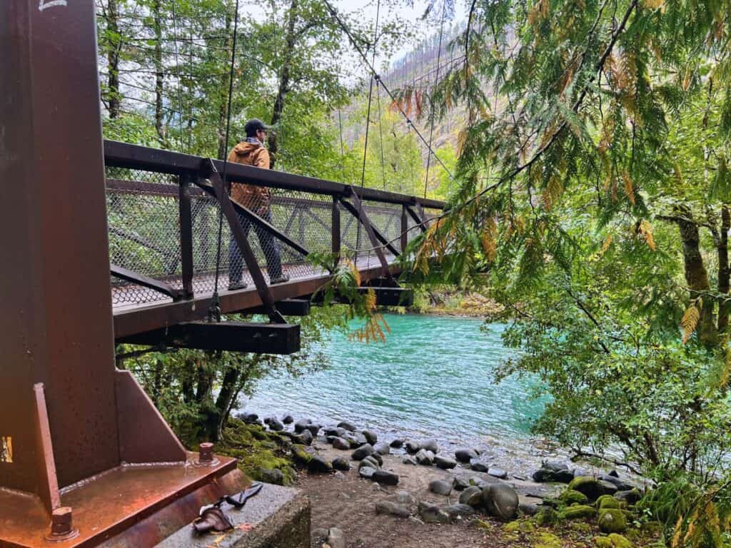A man walks across a footbridge above the Skagit River