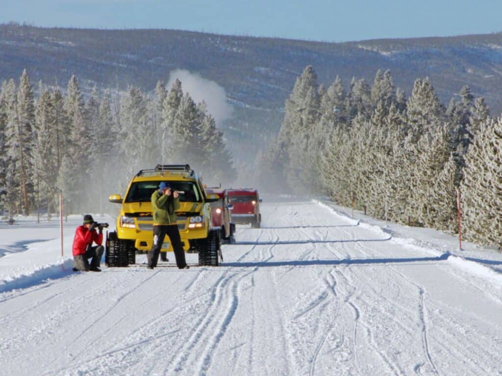 Snowcoaches stop on the road so passengers can get out to take photos of the winter landscape.