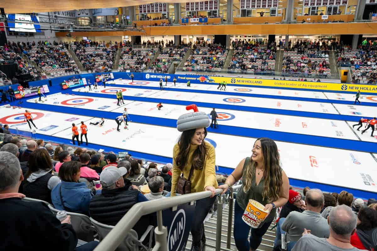Two women climb stadium steps at a women's curling event in Canada.
