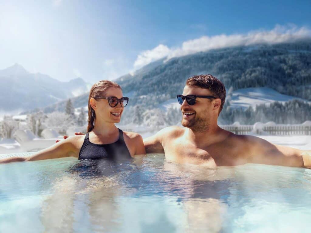 A couple enjoys a mountain hot tub soak in winter.