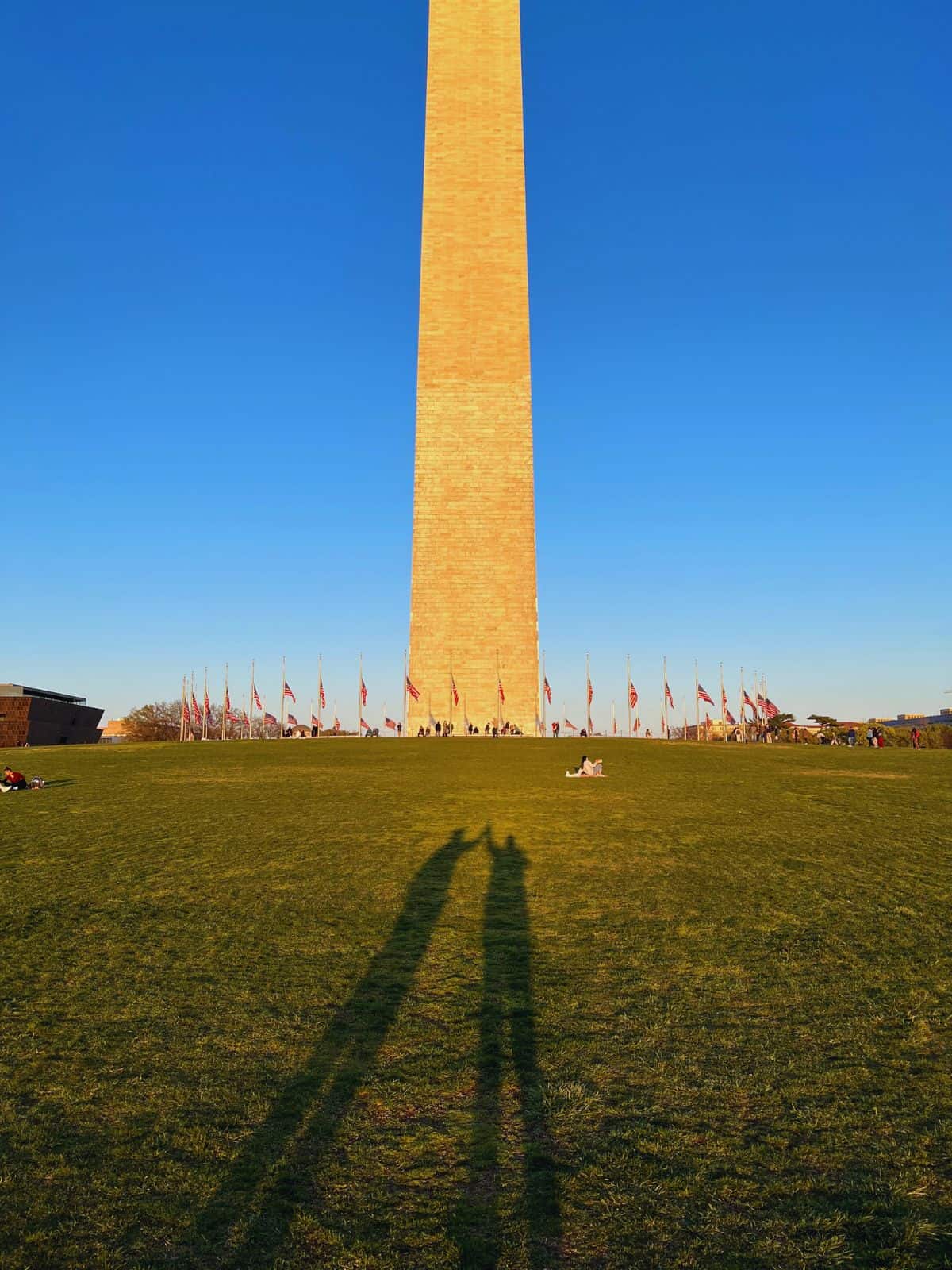 A man and woman perform a shadow high five in front of Washington Monument