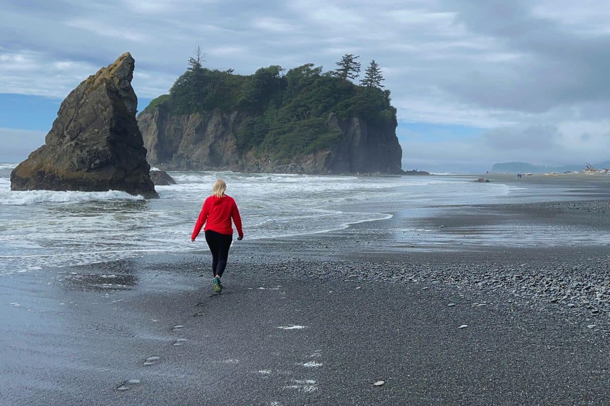 A woman walks toward sea stacks on Ruby Beach, Olympic National Park, WA.