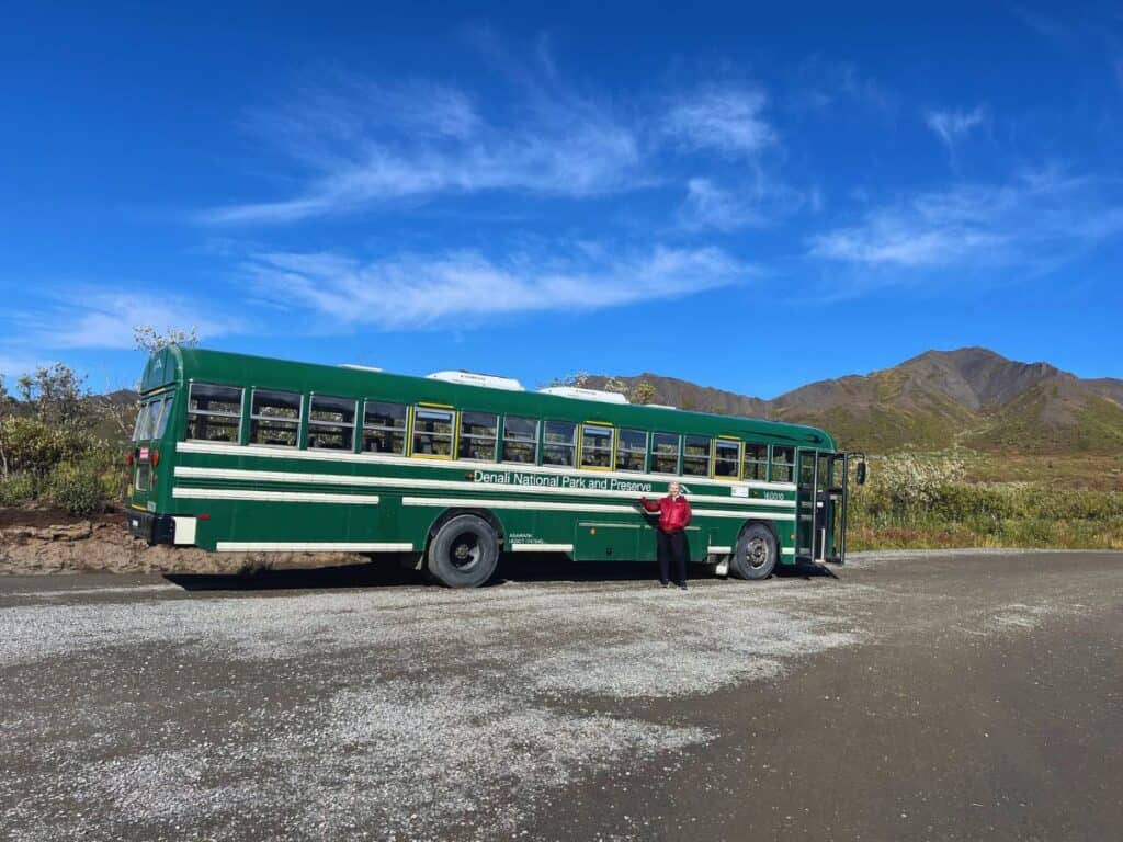A woman points to the name on a green bus in Denali National Park, Alaska.