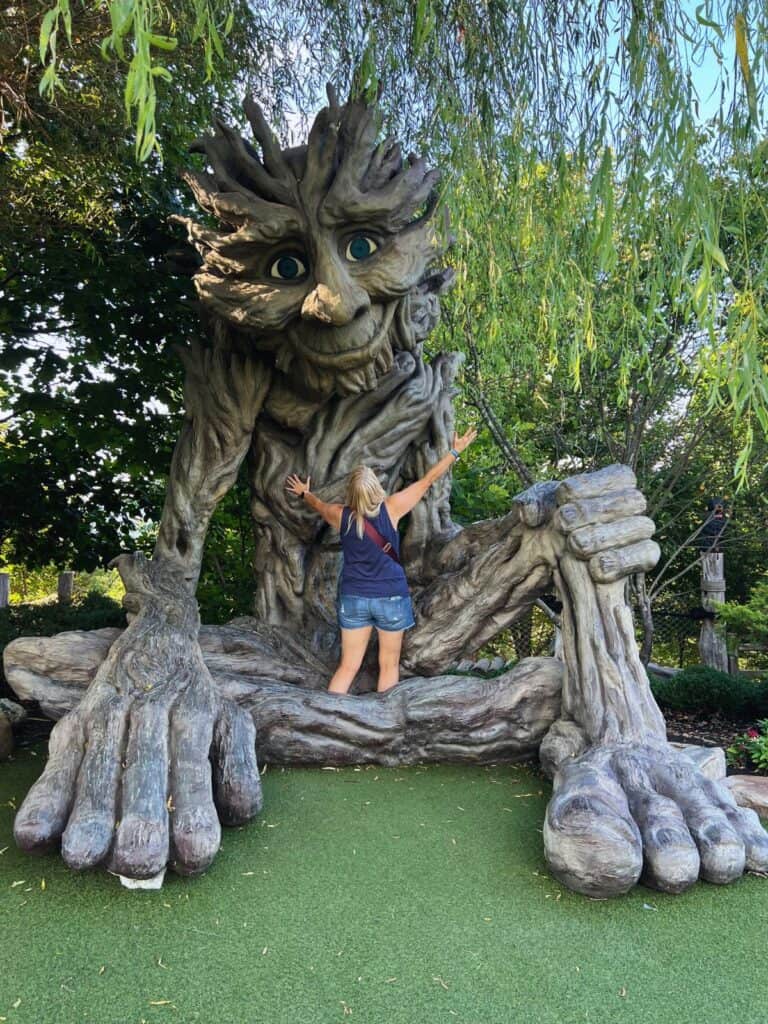 A woman hugs a giant wooden troll in Anakeesta.