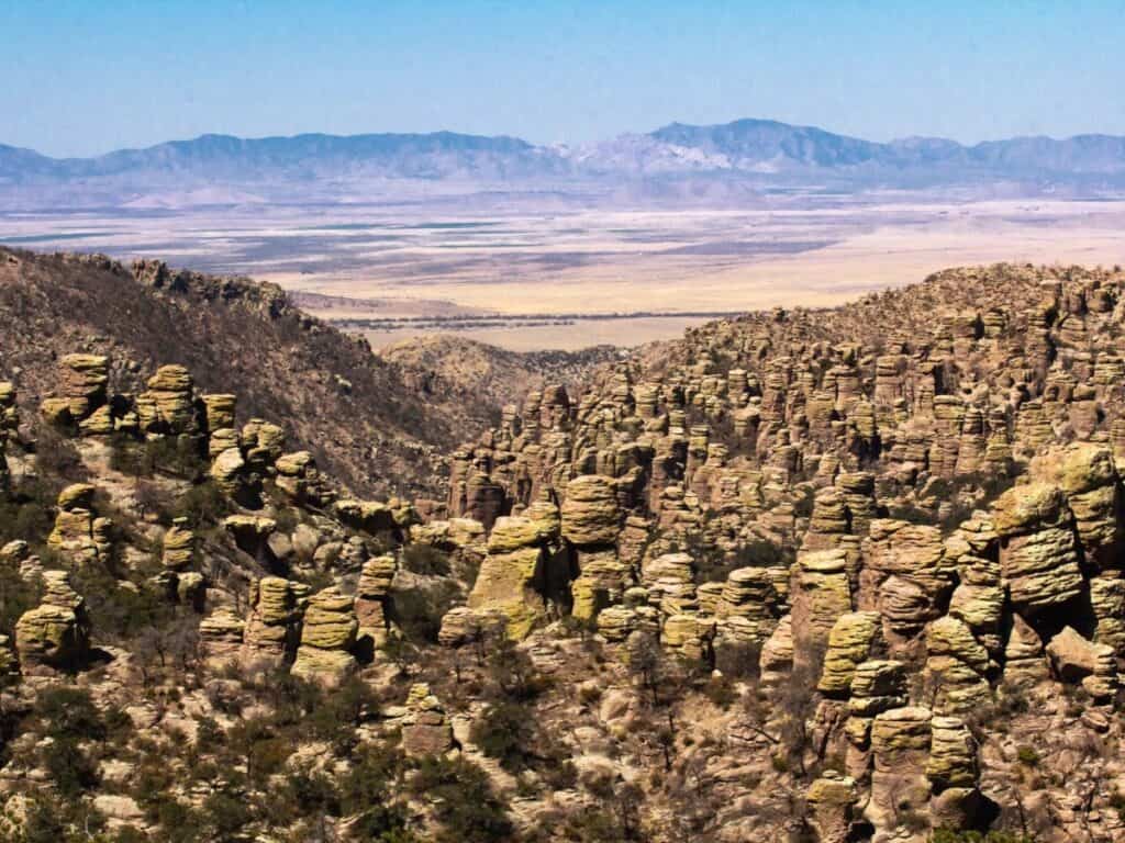 Unique rock formations rise in the foreground with a mountain stretching across the horizon in the background.